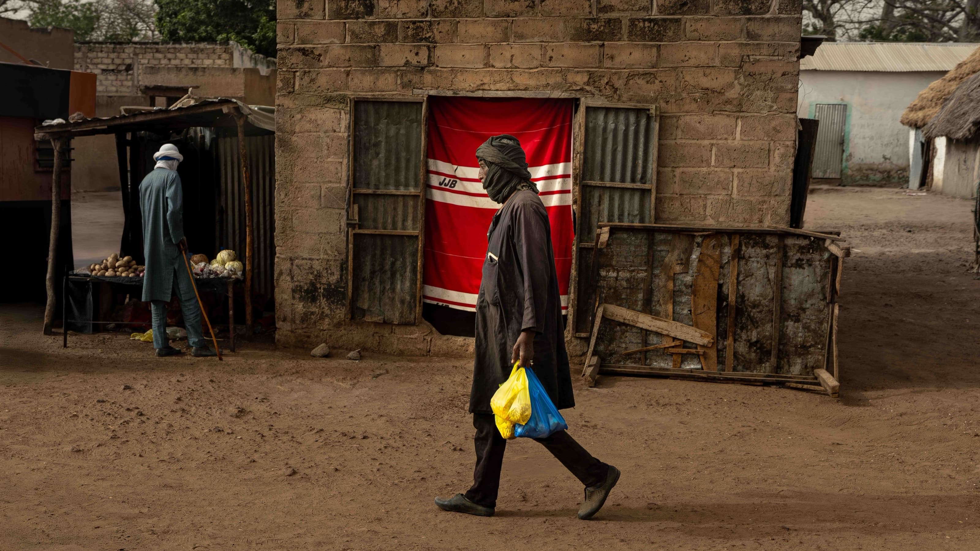 "Primary Colours of Senegal" - a man walking past a red curtained doorway in a Senegalese village