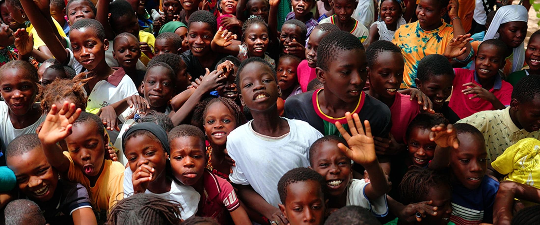 Crowd of children waving and cheering, Senegal