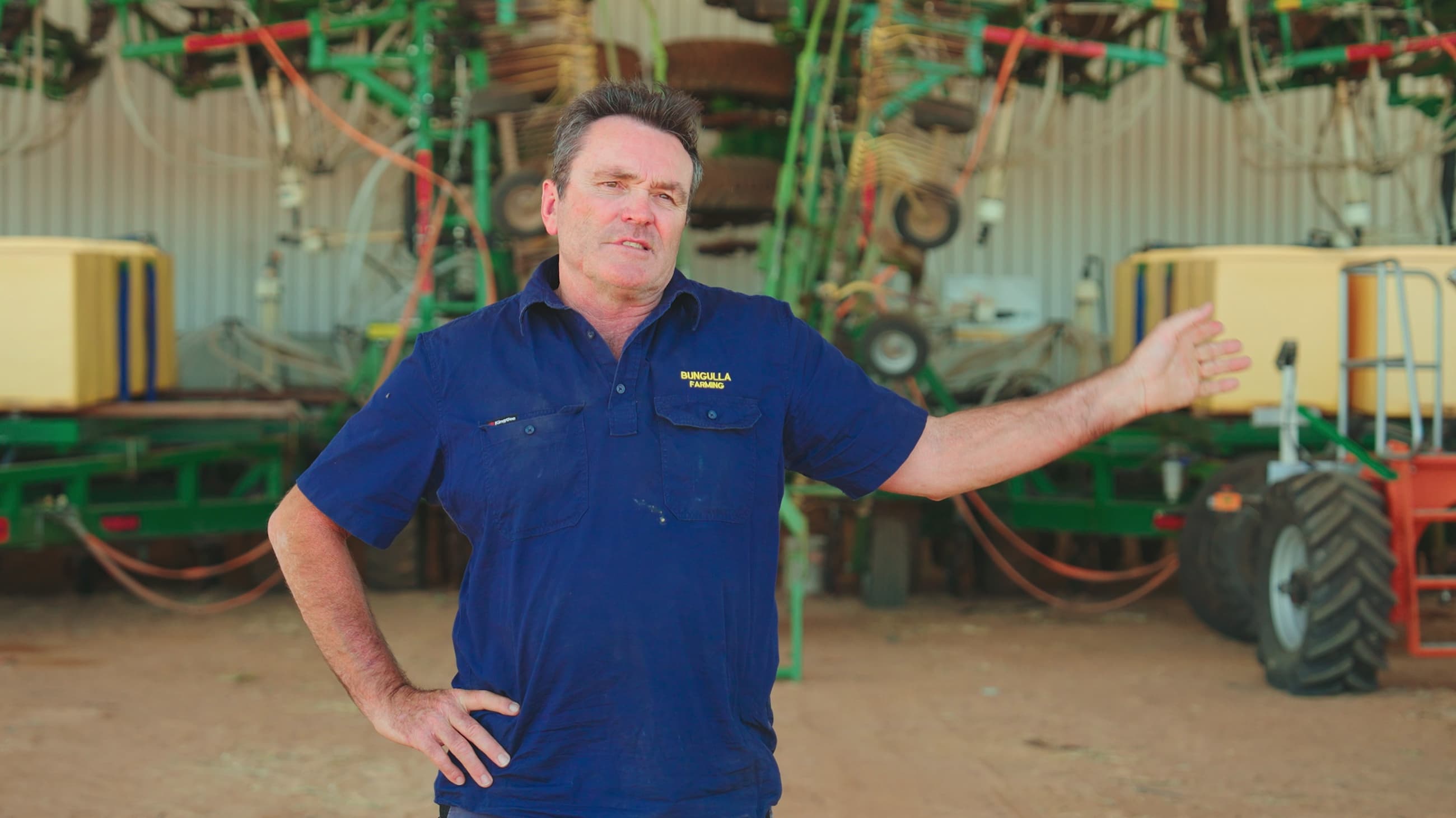 A farmer being interviewed in front of machinery on his property