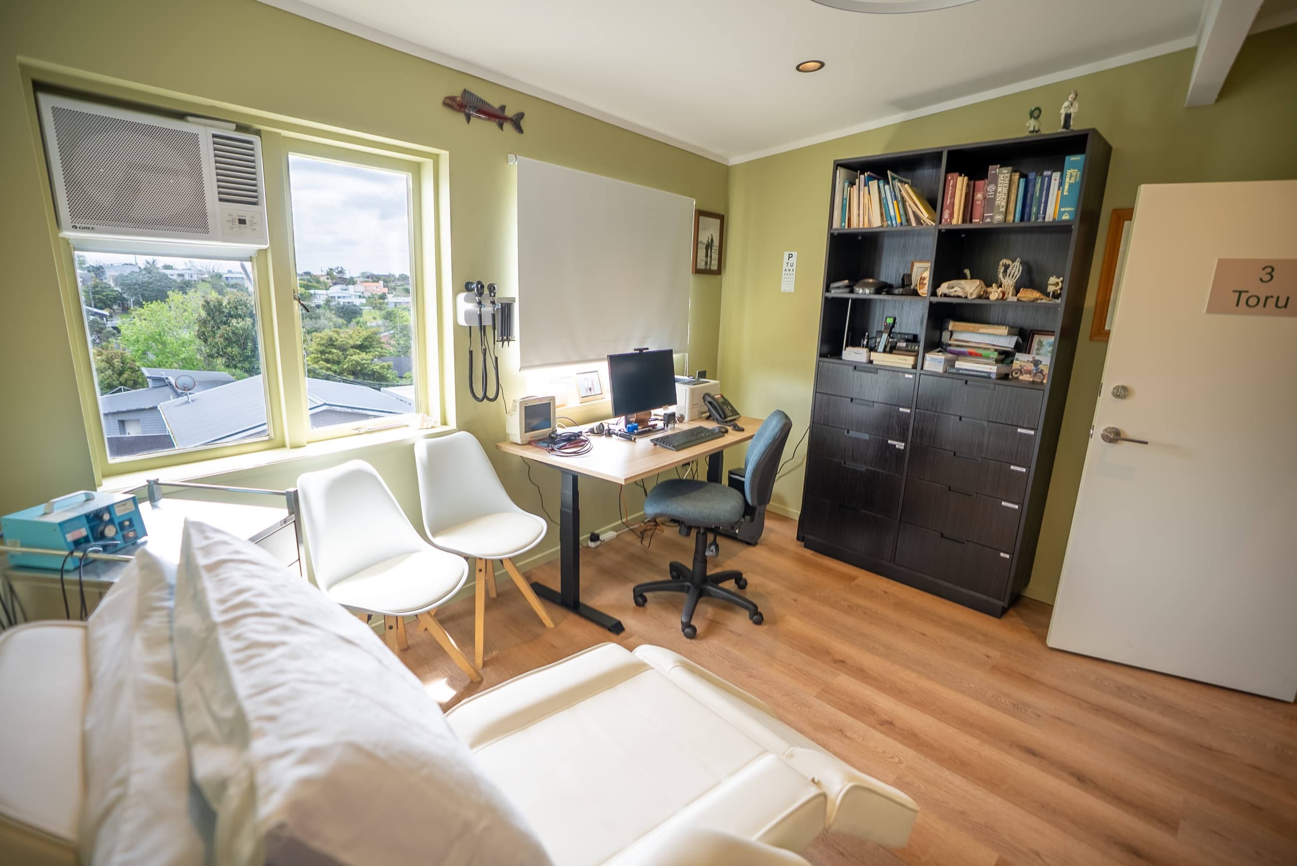 A consult room with desk and examination table
