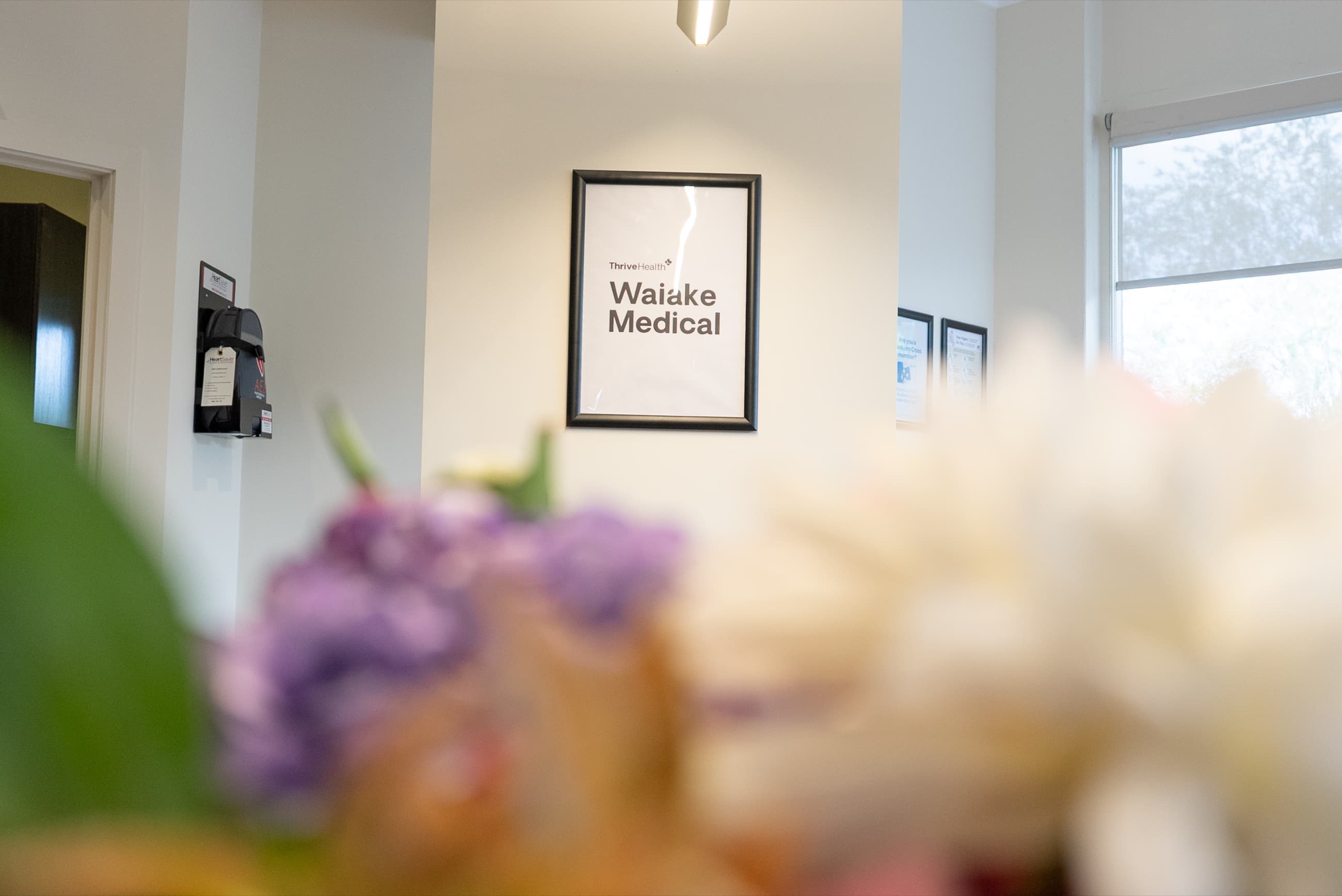 Interior clinic space with Waiake Medical wall signage and flowers