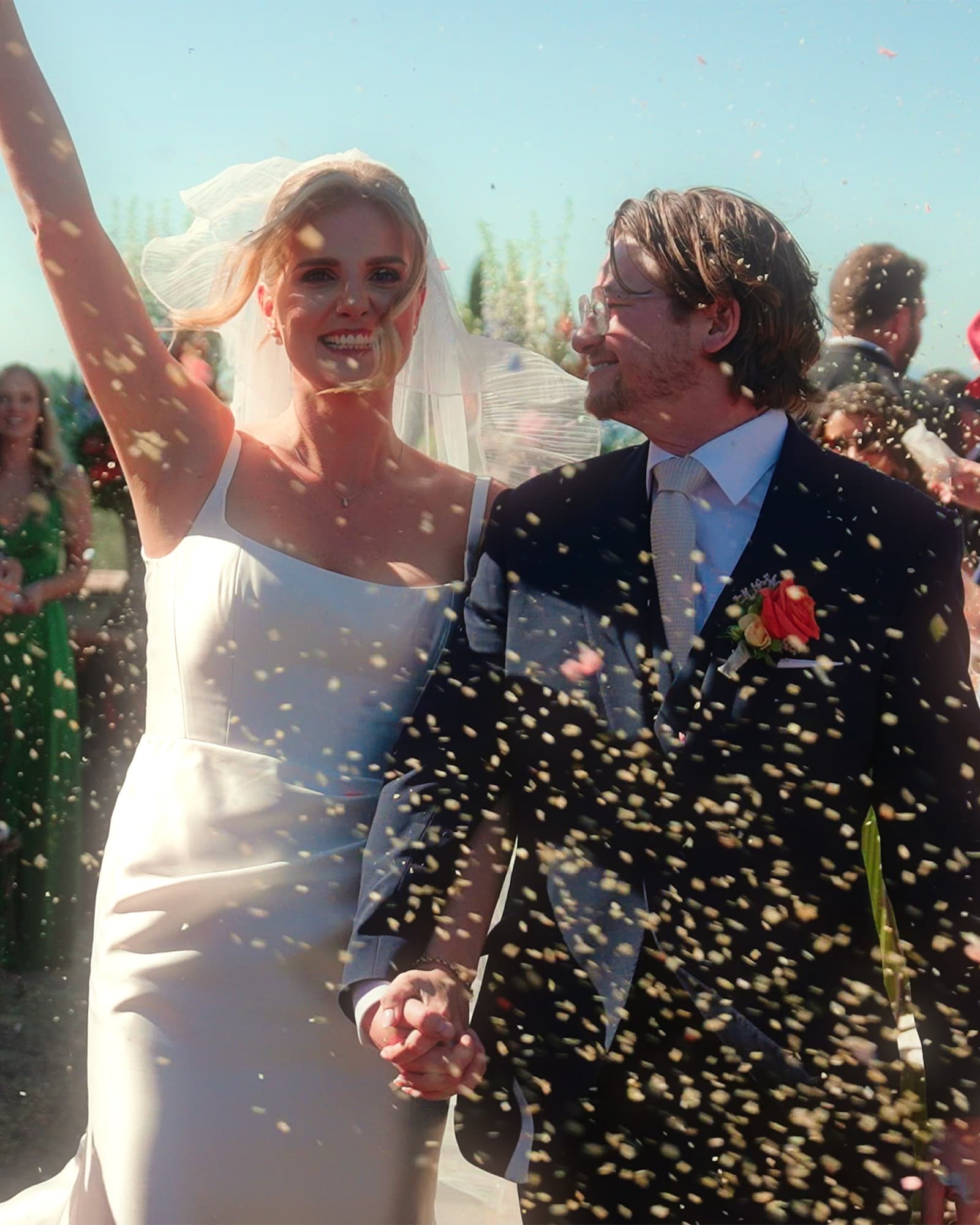 Bride and groom walking hand in hand through confetti