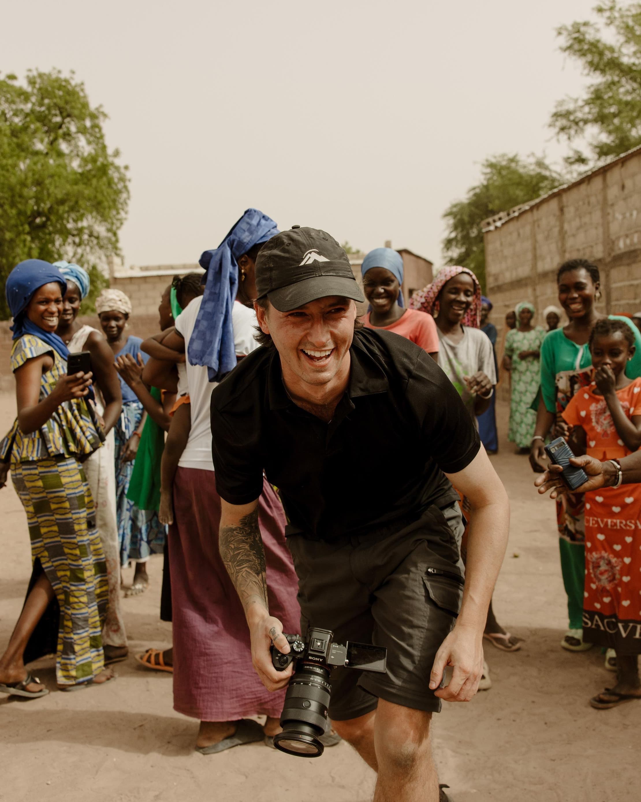 Sam Morgan laughing while filming in the field, camera in hand