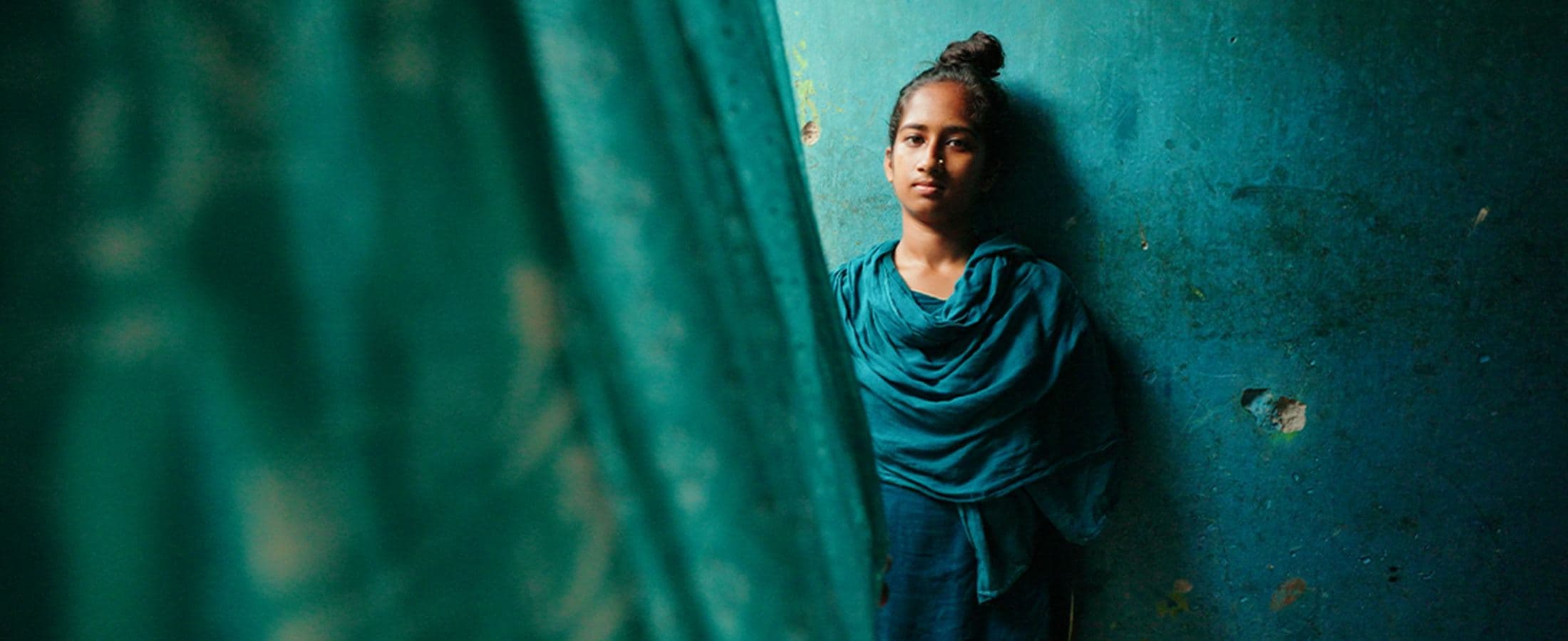 Portrait against a teal wall, Bangladesh