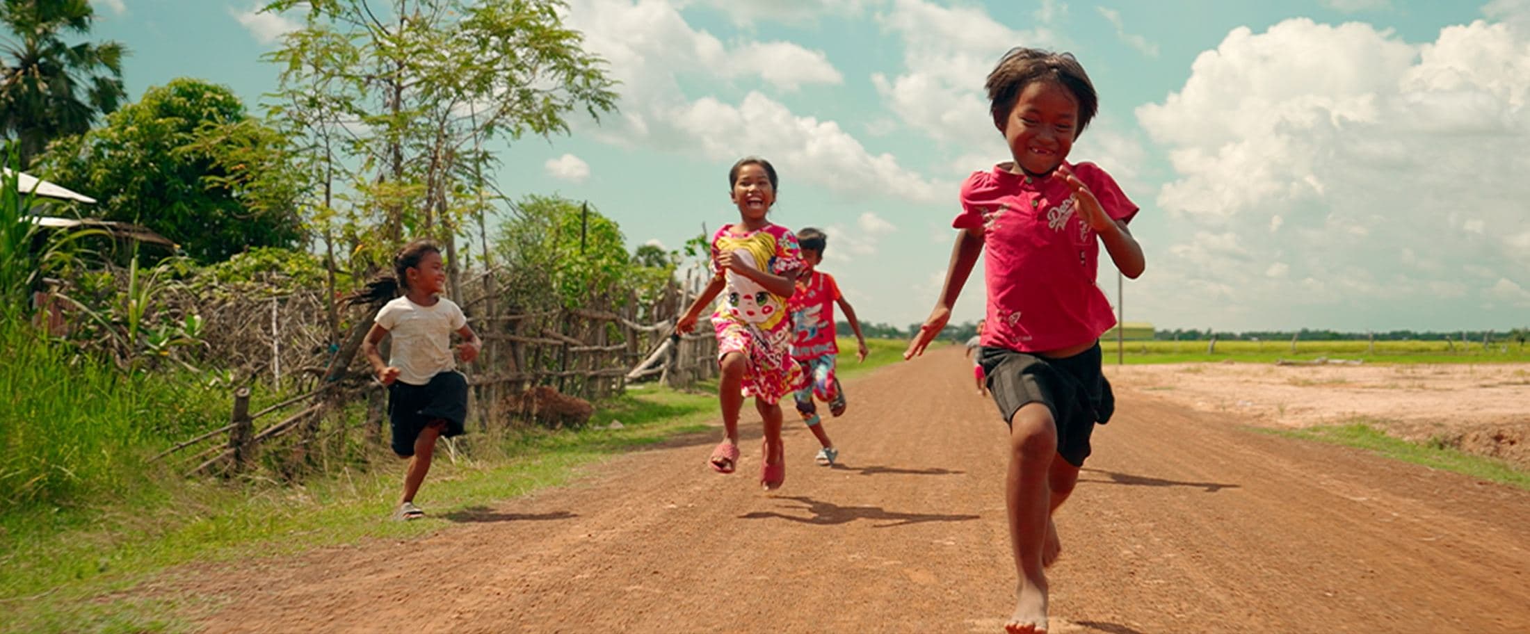 Children running down a dirt road, Cambodia