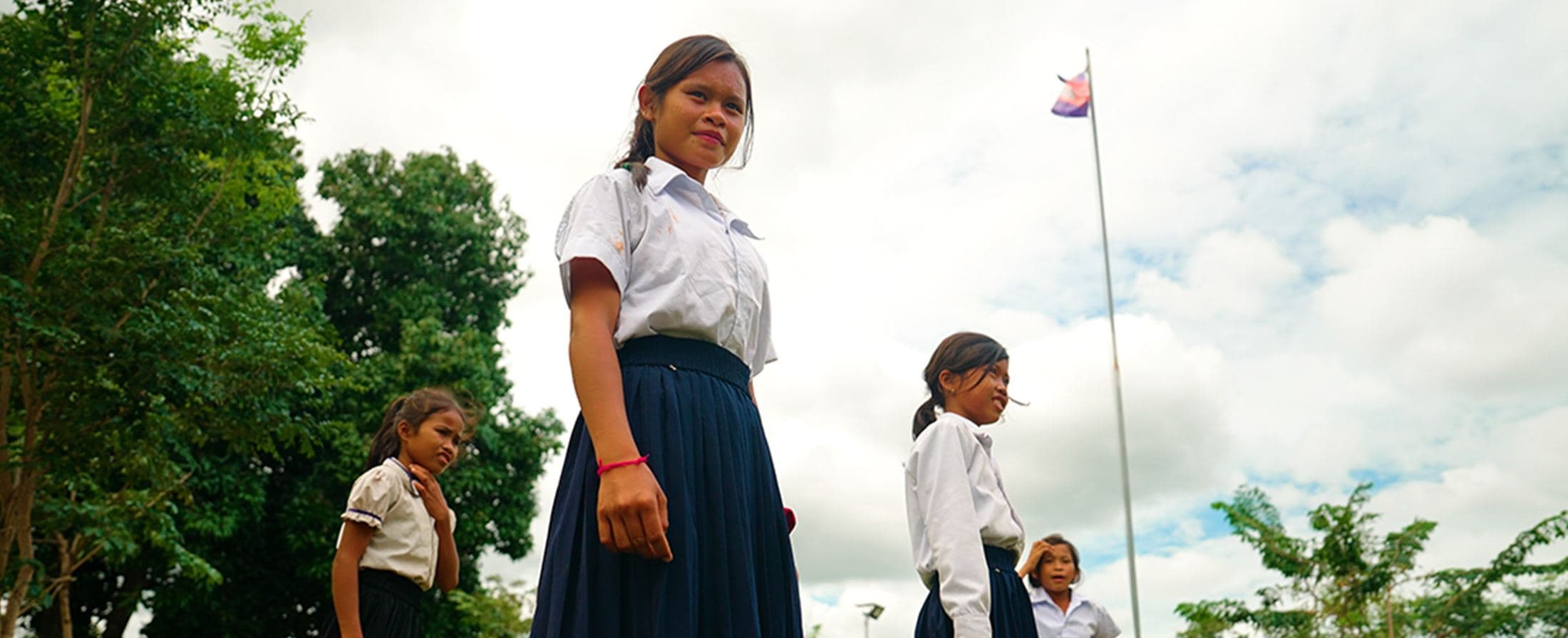 Schoolgirls beside a flagpole, Cambodia