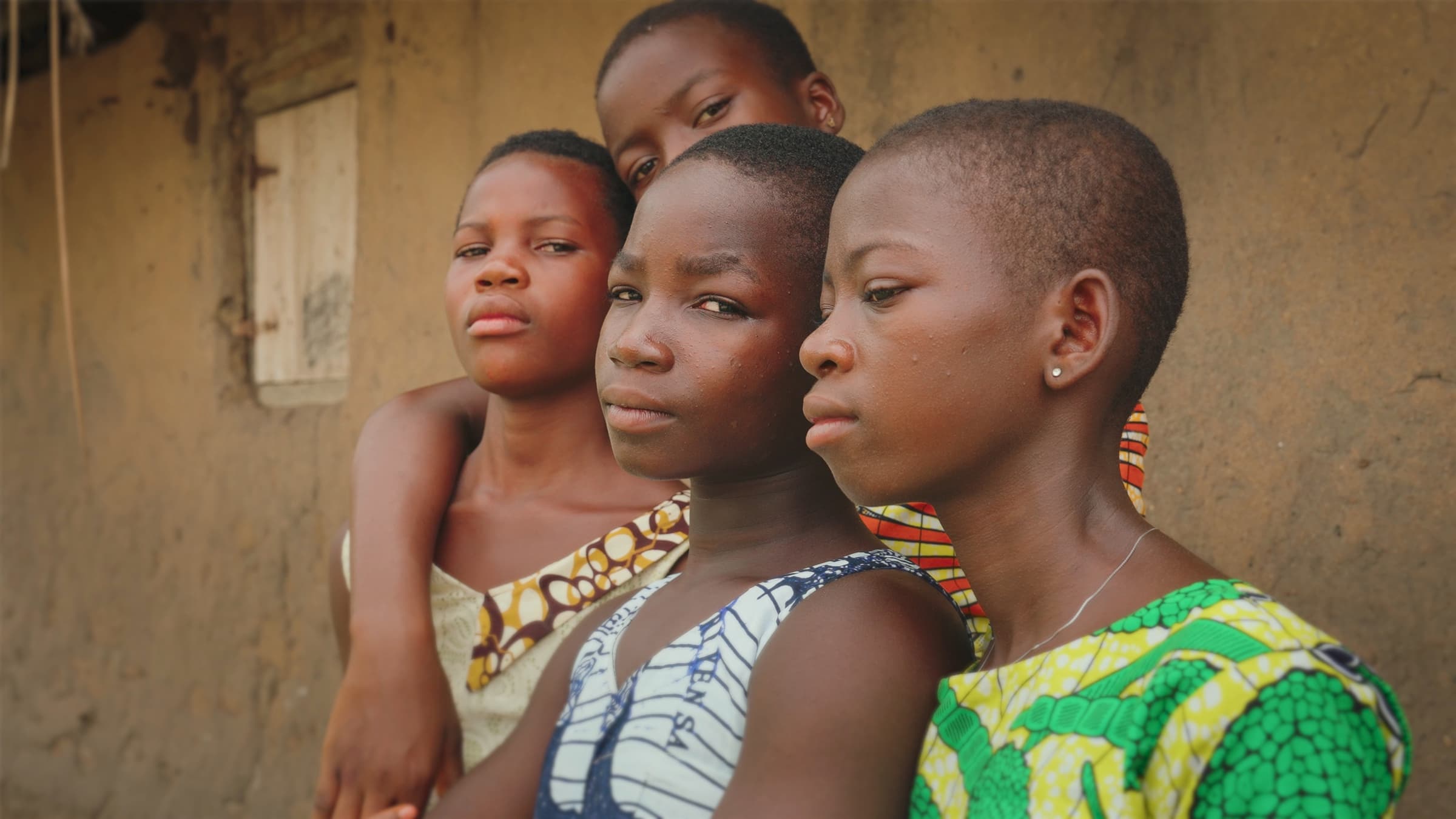 Four young girls in colourful dresses standing together in Ghana