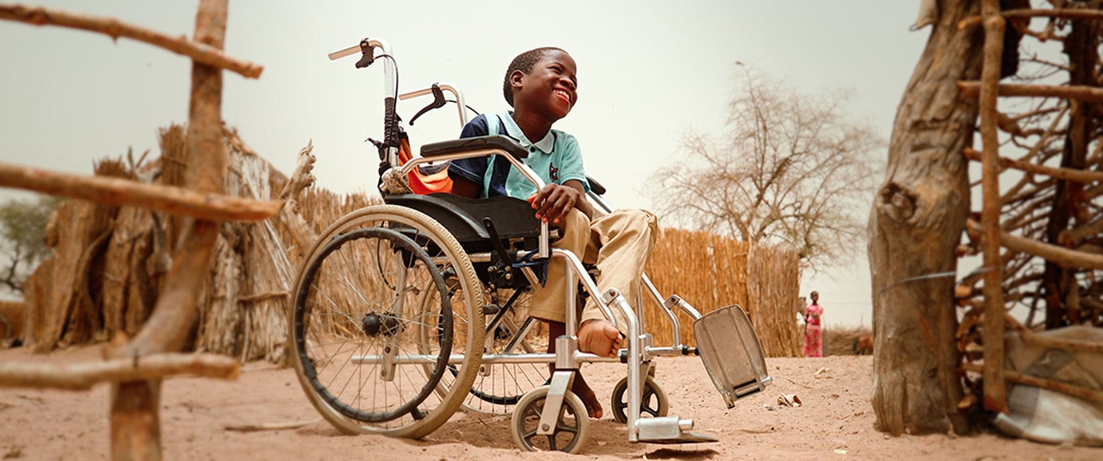 Boy in a wheelchair outside a home, Senegal