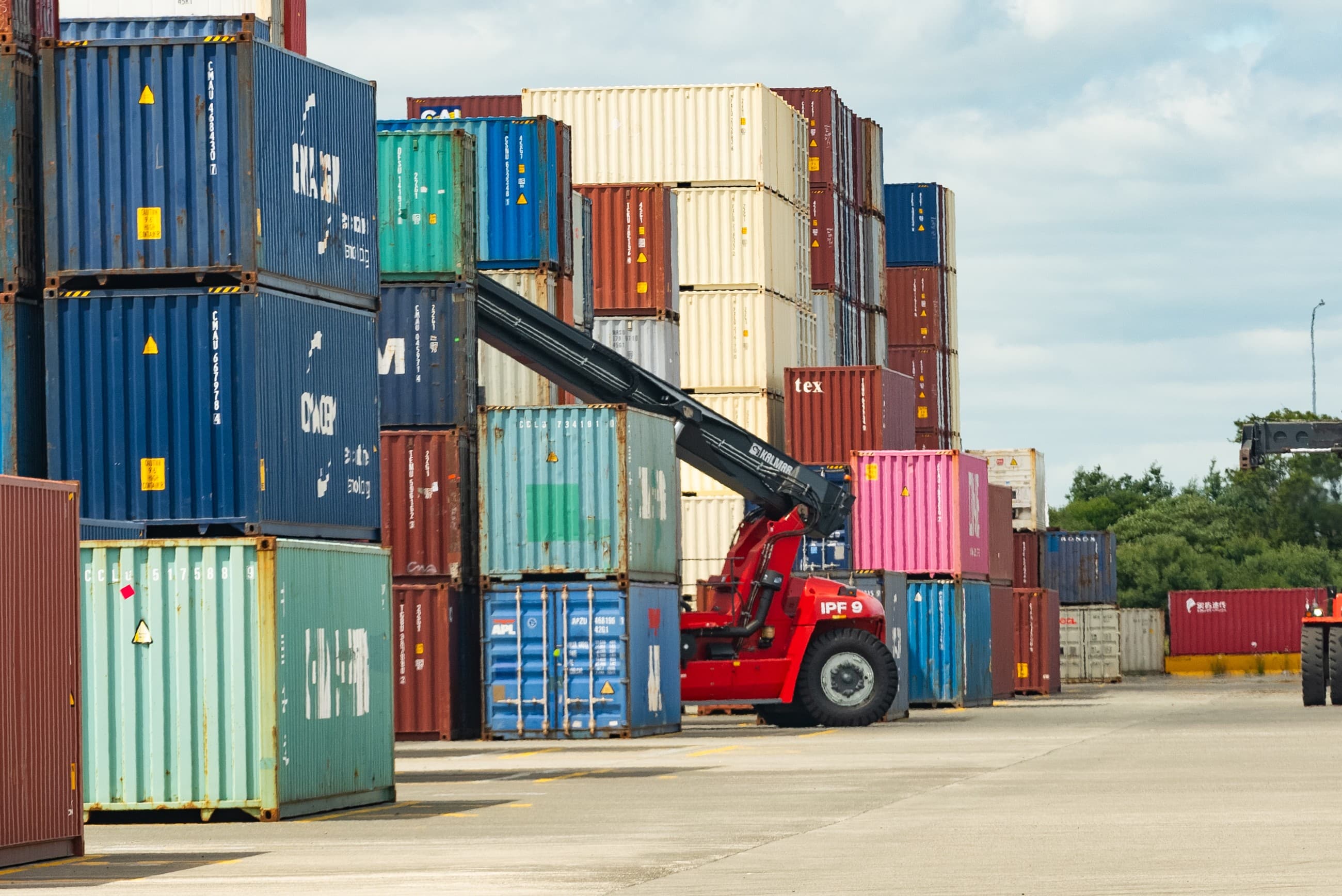Ground-level wide shot of stacked containers and a reach-stacker