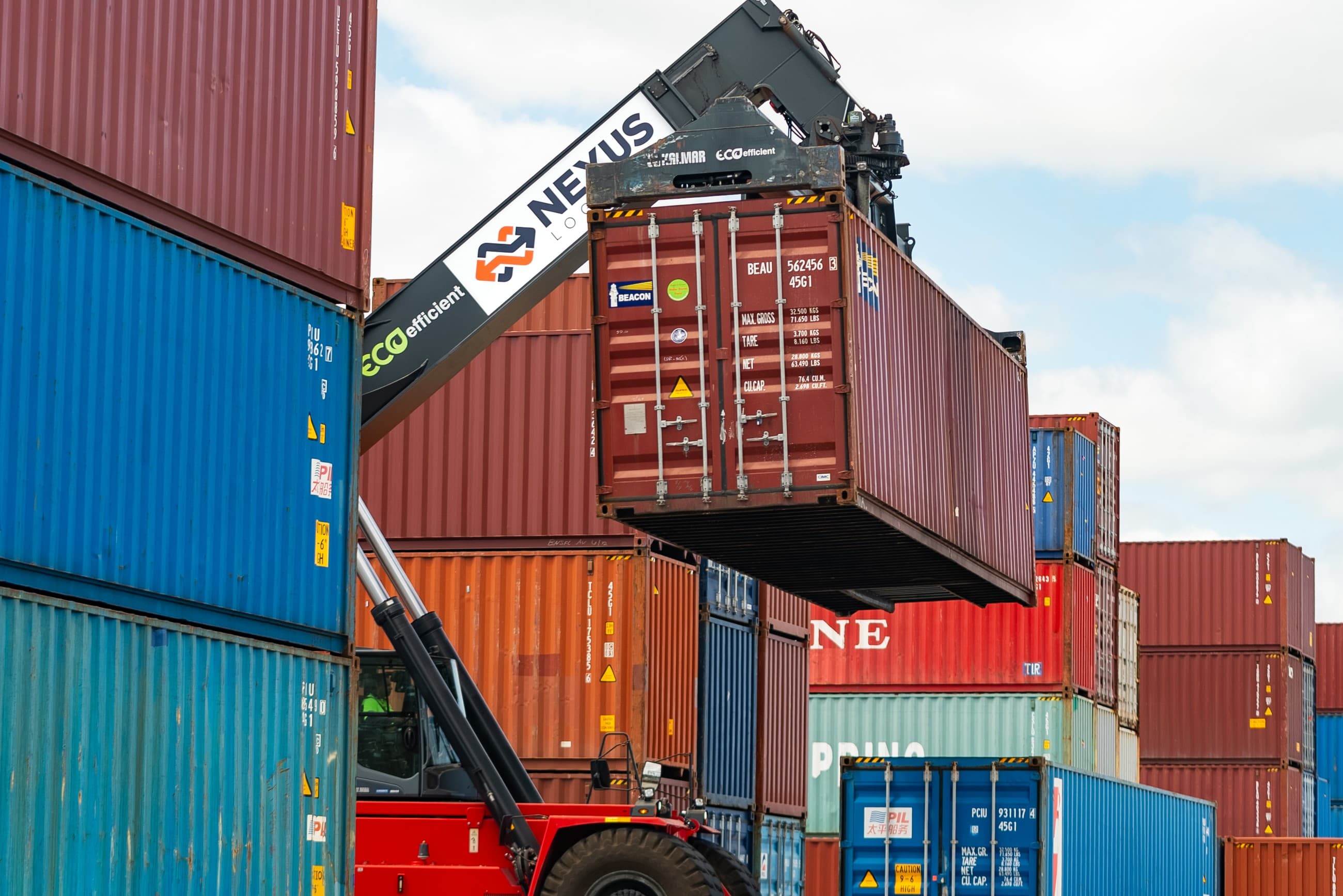 Close-up of the Nexus Logistics branded reach-stacker arm lifting a container